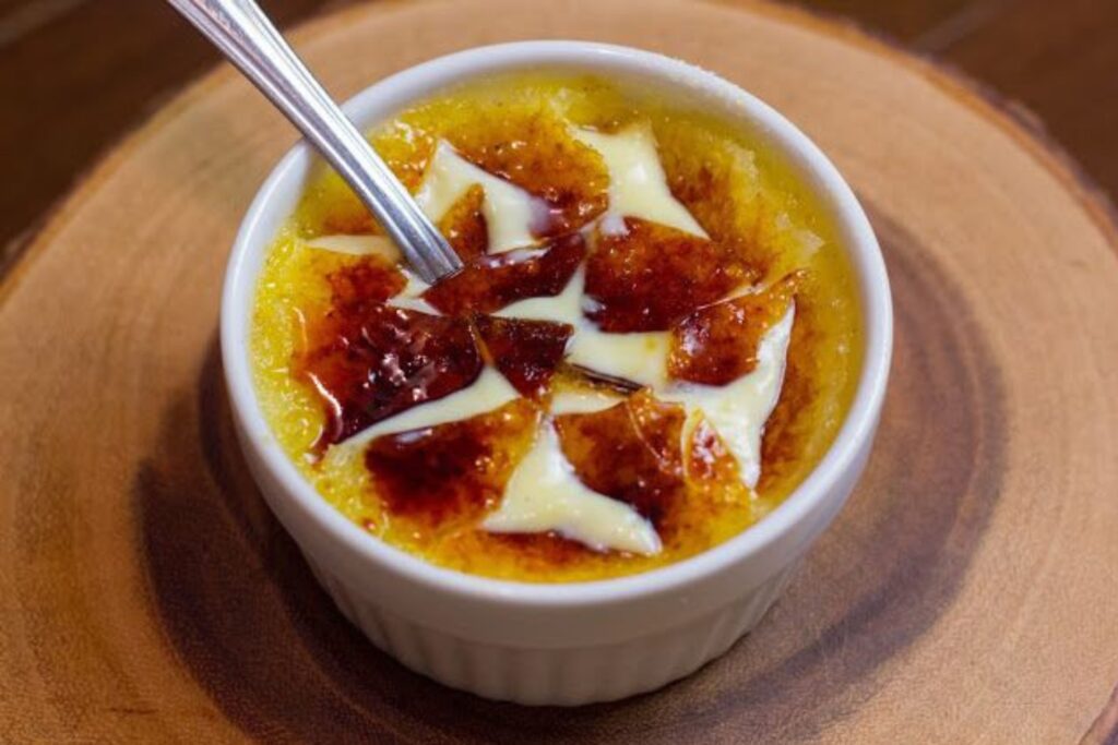 ngredients for crème brûlée, including cream, sugar, and vanilla bean, arranged on a countertop.