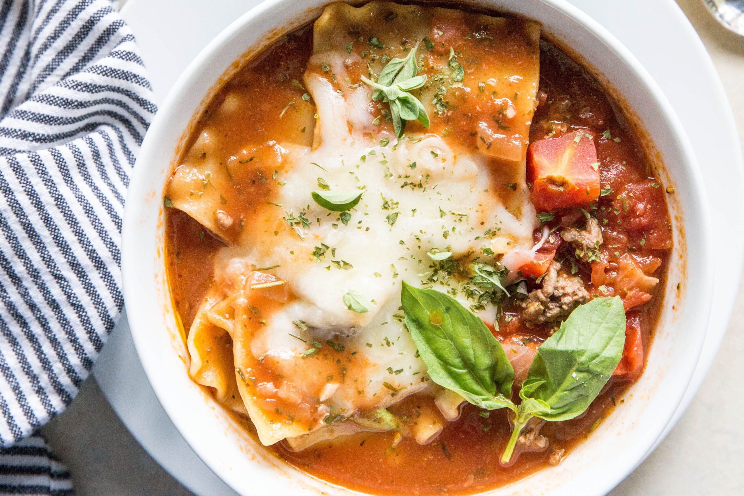 Bowl of hearty Lasagna Soup topped with cheese and basil.